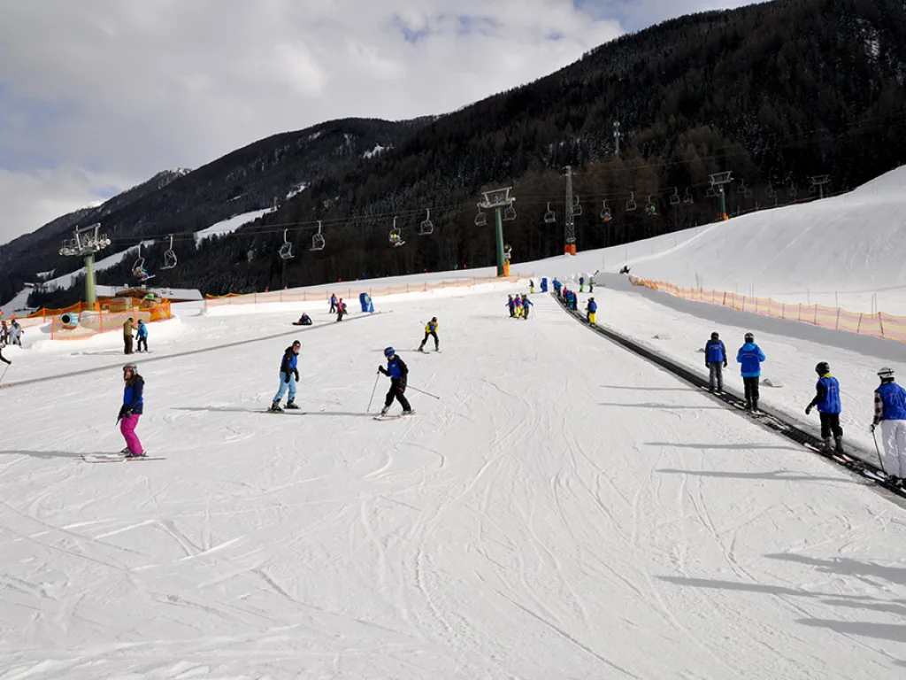 Blick über den Übungshang mit Förderband und Lernenden.